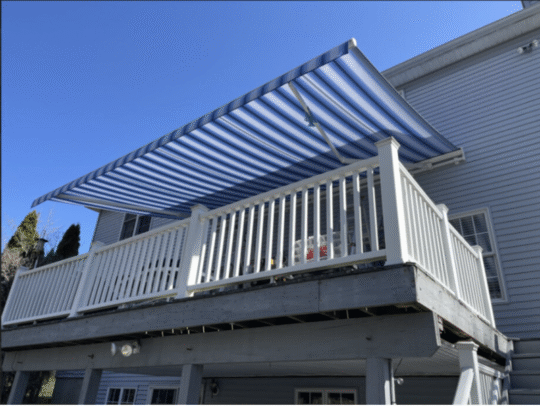 Image of a blue striped awning over a white deck.